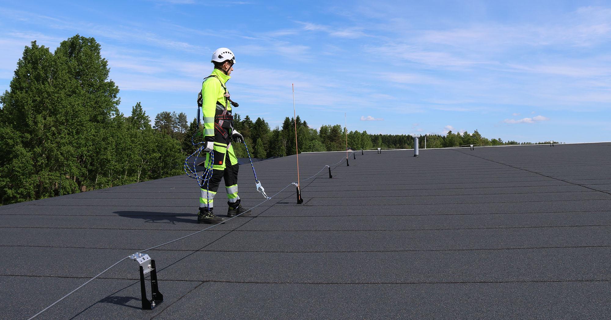 Kuvassa huoltomies kytkeytyneenä Pisko SafeLine vaijerijärjestelmään huopakatolla ja näin pystyy totetuaamaan katon huoltotyöt turvallisesti.